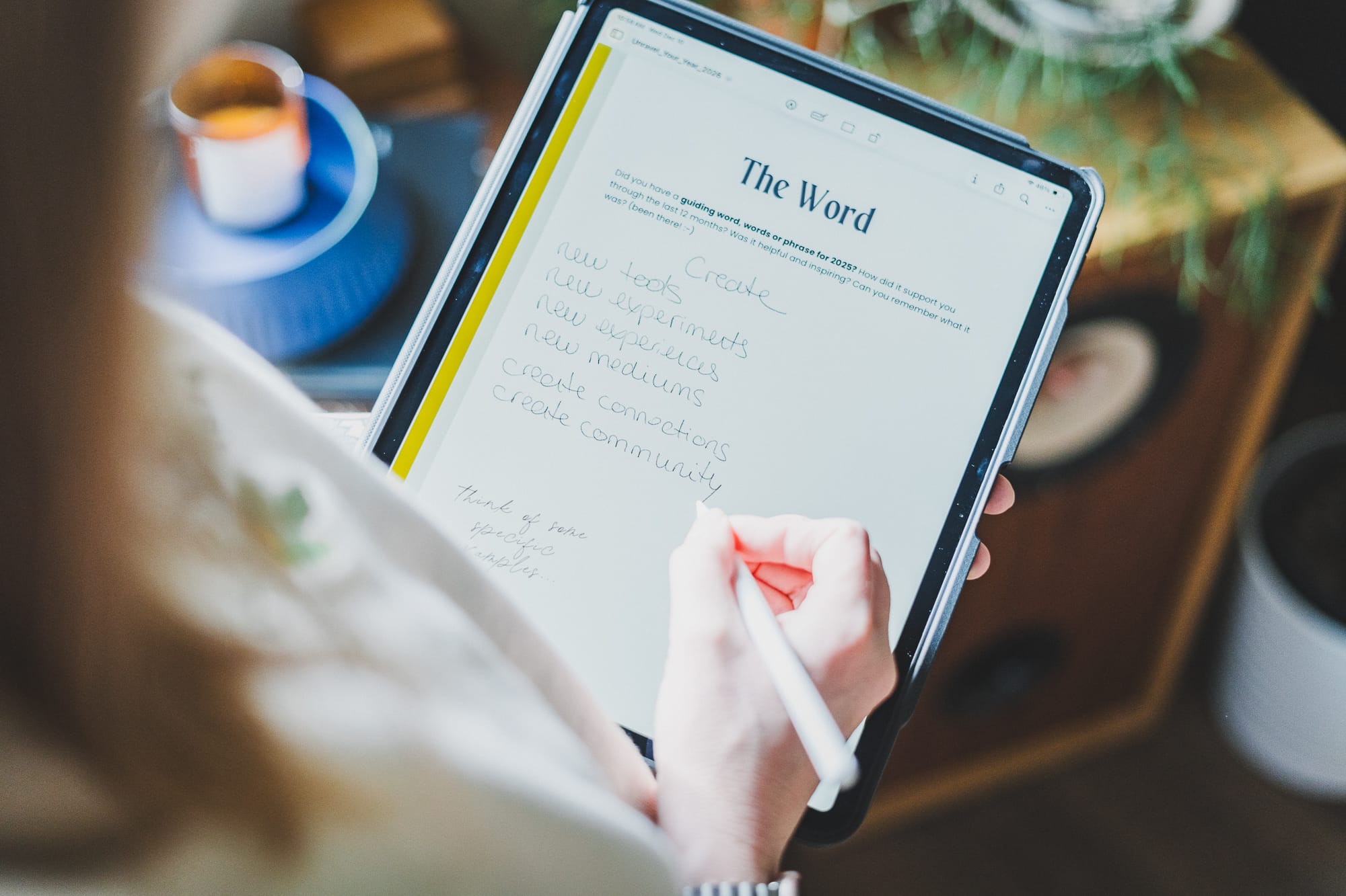 Close-up of someone writing on their iPad in the “The Word” section of Unravel Your Year 2026, jotting ideas like “create,” “new experiments,” and “create community” with a stylus.